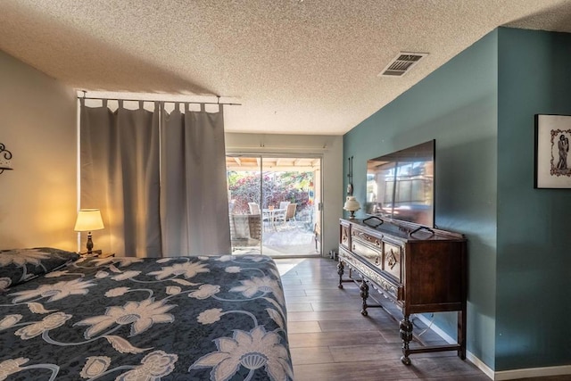 bedroom featuring a textured ceiling, access to outside, and hardwood / wood-style flooring