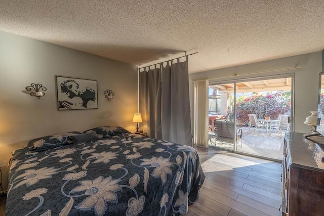 bedroom with access to outside, a textured ceiling, and light hardwood / wood-style flooring