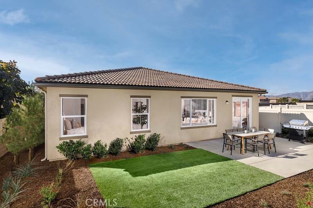 rear view of property featuring a lawn and a patio