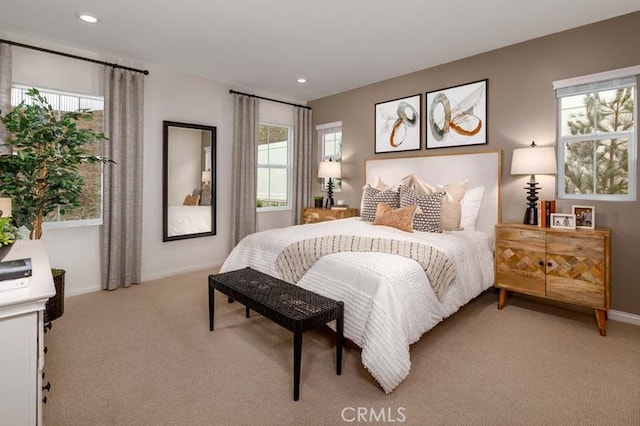 bedroom featuring light colored carpet and multiple windows