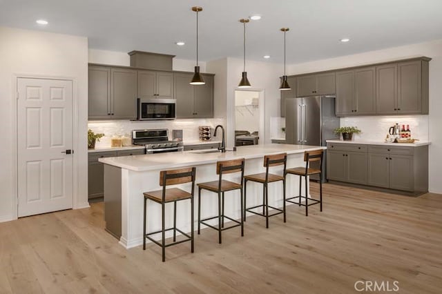 kitchen featuring light hardwood / wood-style flooring, a breakfast bar, a center island with sink, and appliances with stainless steel finishes