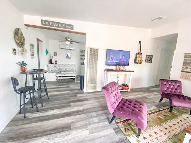 61974 Terrace Dr, Joshua Tree, CA 92252 - living area with a wall mounted air conditioner, a heating unit, wood finished floors, and a ceiling fan