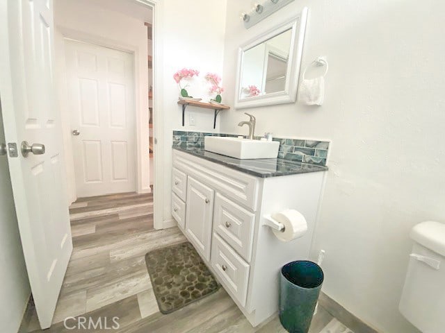 bathroom with hardwood / wood-style floors, vanity, and toilet