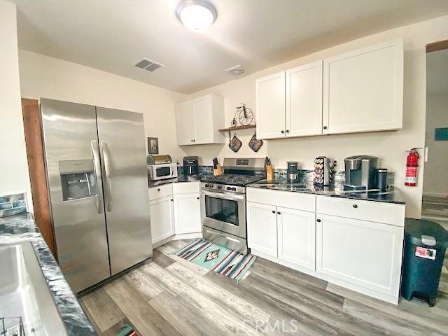 61974 Terrace Dr, Joshua Tree, CA 92252 - kitchen featuring stainless steel appliances, white cabinets, light wood-style flooring, and dark countertops