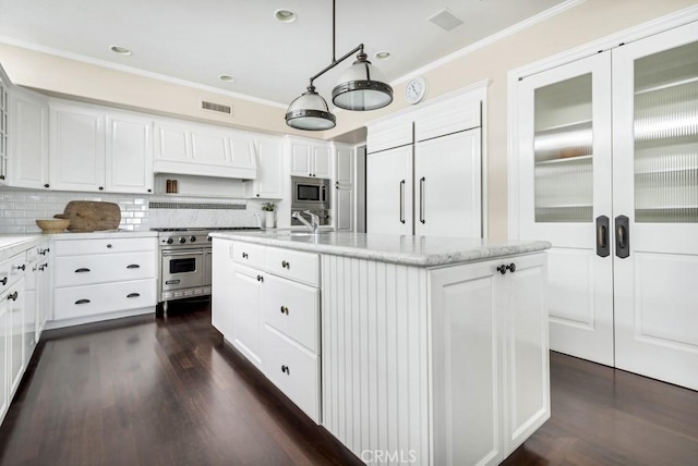 kitchen featuring a kitchen island with sink, white cabinets, decorative light fixtures, dark hardwood / wood-style flooring, and stainless steel appliances