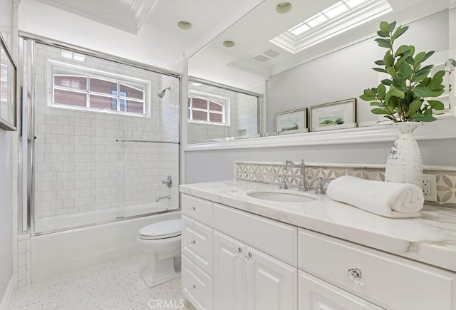 full bathroom with vanity, toilet, crown molding, and enclosed tub / shower combo