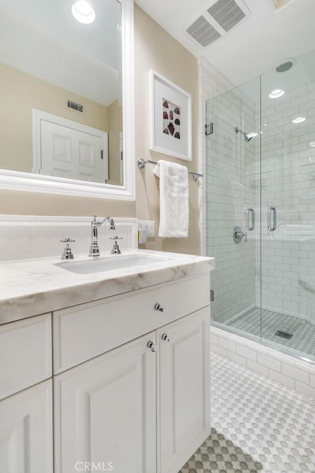 bathroom featuring vanity and a shower with door