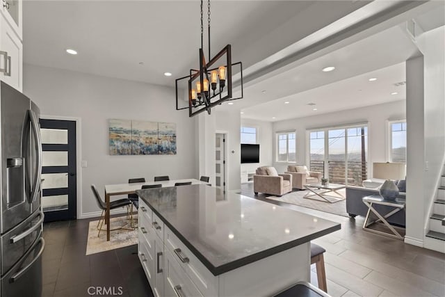 kitchen with white cabinetry, a kitchen island, a breakfast bar area, and stainless steel fridge