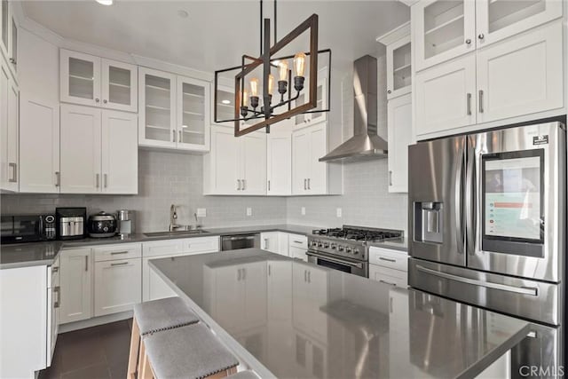 kitchen featuring sink, wall chimney range hood, pendant lighting, stainless steel appliances, and white cabinets