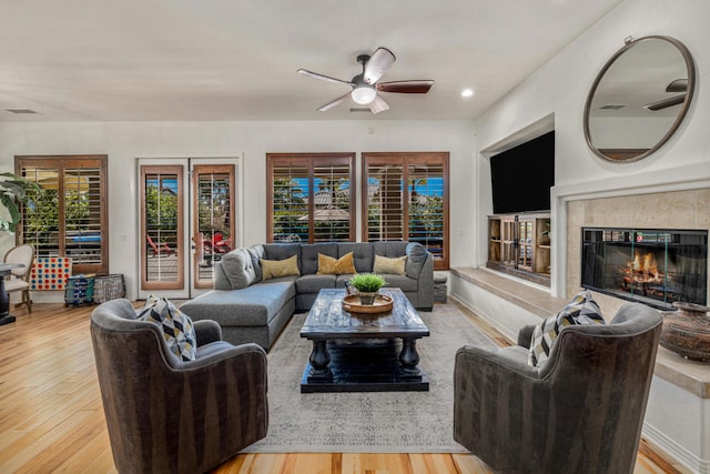 living room with a fireplace, ceiling fan, and light hardwood / wood-style flooring