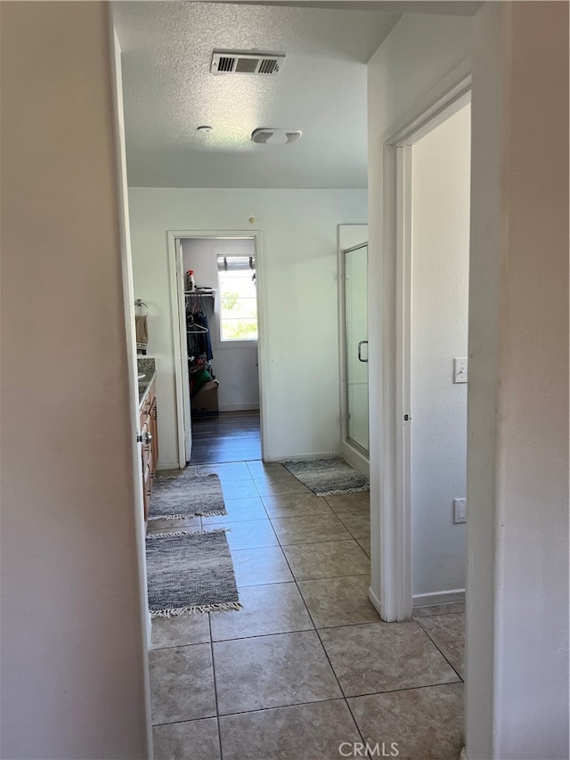 hallway featuring a textured ceiling and light tile patterned floors