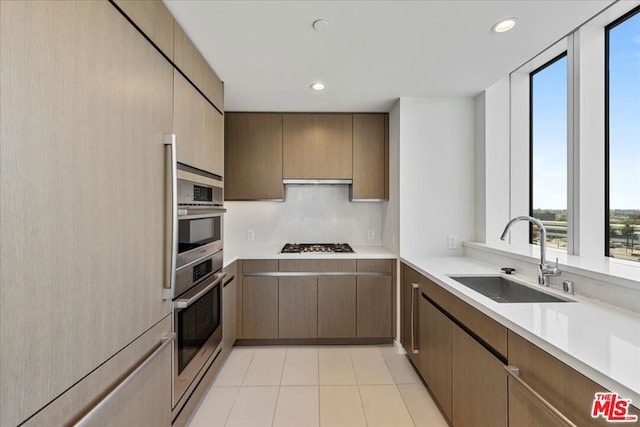 kitchen featuring range hood, stainless steel appliances, light tile patterned floors, and sink