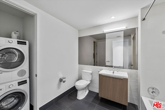 full bathroom featuring vanity, tile patterned flooring, shower / bath combination, stacked washer and dryer, and toilet