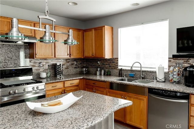 kitchen featuring light stone counters, hanging light fixtures, sink, appliances with stainless steel finishes, and decorative backsplash