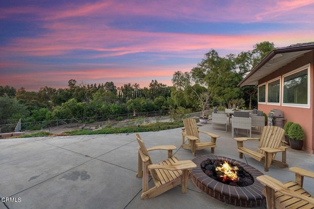 patio terrace at dusk with area for grilling and an outdoor living space with a fire pit