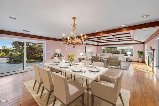 dining room with beamed ceiling, a healthy amount of sunlight, a notable chandelier, and light wood-type flooring