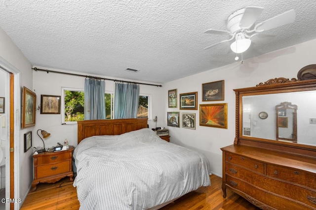 bedroom featuring ceiling fan, wood-type flooring, and a textured ceiling