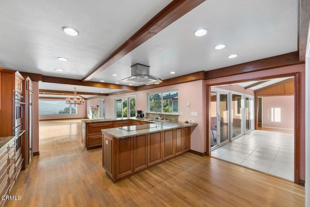 kitchen with kitchen peninsula, beamed ceiling, and light hardwood / wood-style floors