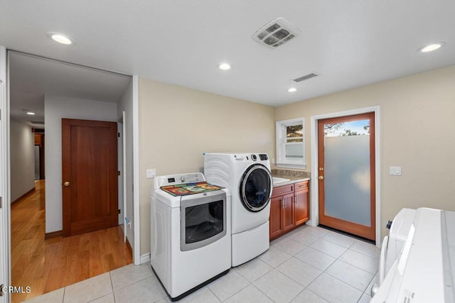 laundry room with separate washer and dryer, light tile patterned floors, and cabinets