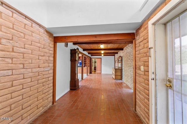 hallway featuring beamed ceiling and brick wall