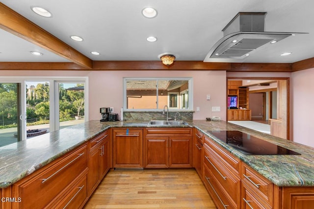 kitchen featuring kitchen peninsula, light stone countertops, black electric cooktop, sink, and light hardwood / wood-style floors