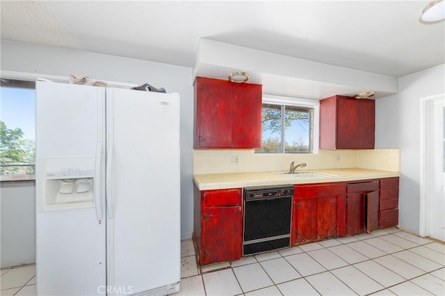10925 Post Office Rd A/B, Unit A/B, Lucerne Valley, CA 92356 - kitchen featuring white refrigerator with ice dispenser, black dishwasher, tasteful backsplash, a sink, and red cabinets