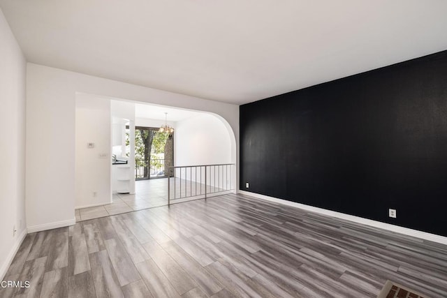 empty room with hardwood / wood-style floors and a notable chandelier