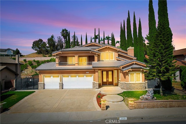 view of front of property with a lawn, a balcony, french doors, and a garage