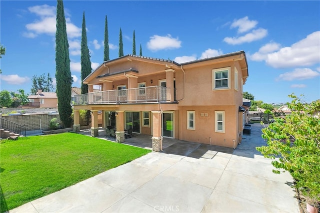 back of property featuring a lawn, a patio, and a balcony