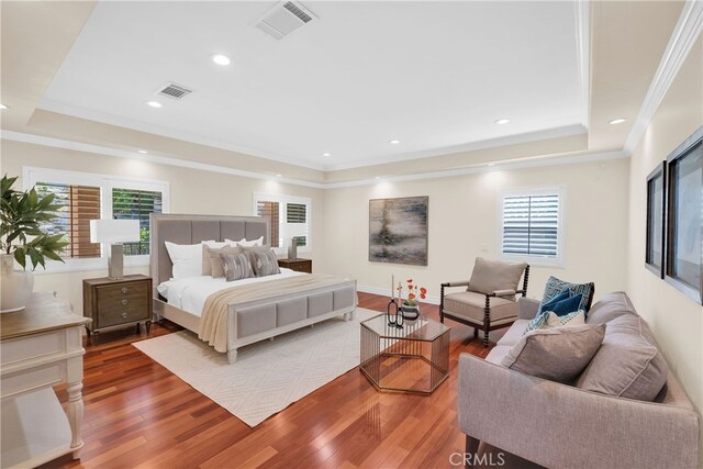 bedroom featuring a raised ceiling, ornamental molding, and hardwood / wood-style flooring