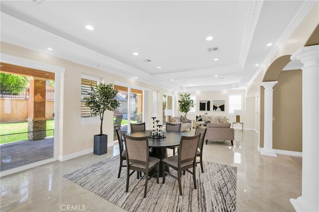 dining room with ornamental molding, a raised ceiling, and ornate columns