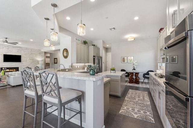 kitchen featuring kitchen peninsula, ceiling fan, appliances with stainless steel finishes, pendant lighting, and a breakfast bar