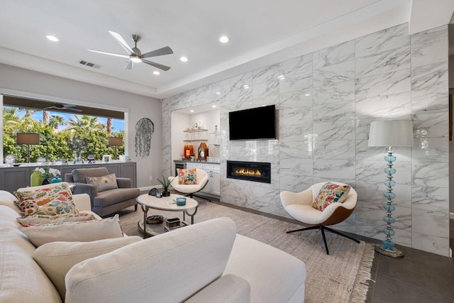 living room with ceiling fan, tile walls, and a fireplace