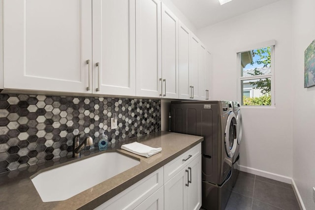 clothes washing area with dark tile patterned floors, sink, independent washer and dryer, and cabinets