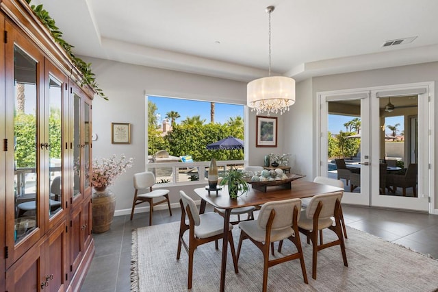 dining area featuring dark tile patterned floors, french doors, and a chandelier