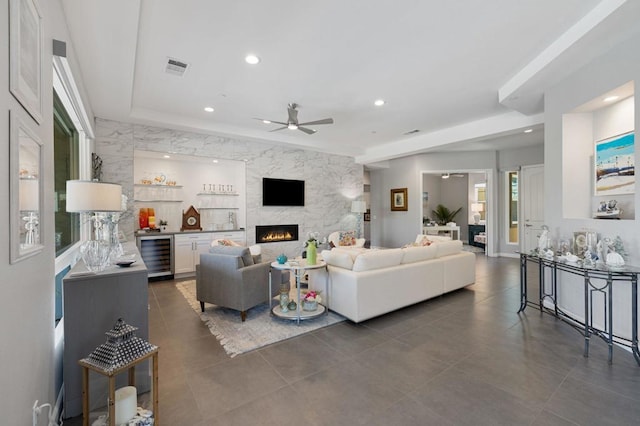 living room with ceiling fan, beverage cooler, and a fireplace