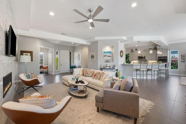 living room featuring ceiling fan, a wealth of natural light, and a fireplace