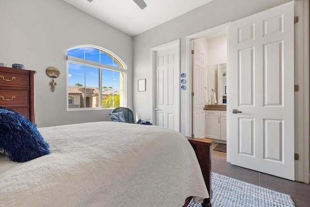 bedroom featuring ensuite bath, ceiling fan, dark tile patterned floors, and lofted ceiling