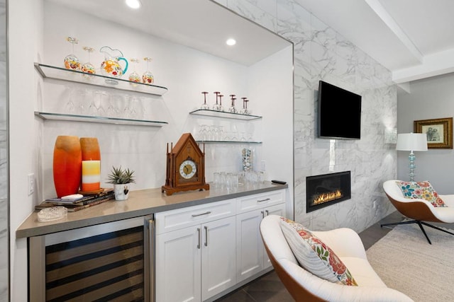 bar with tile walls, white cabinets, a high end fireplace, and wine cooler