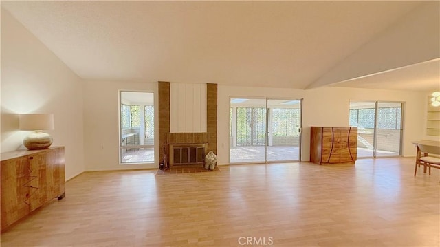 unfurnished living room featuring lofted ceiling, a wealth of natural light, and light hardwood / wood-style floors