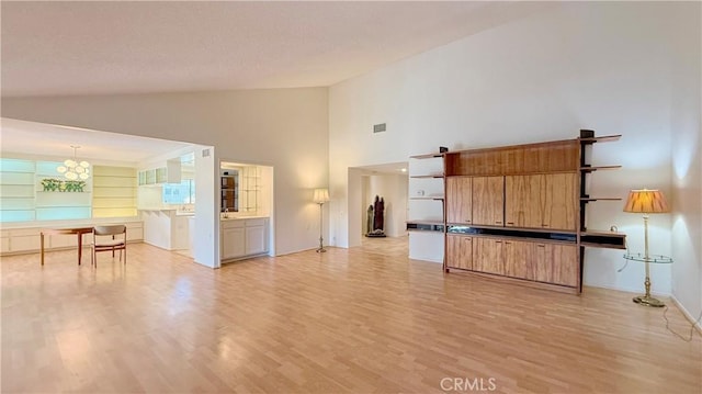 unfurnished living room featuring light wood-type flooring, high vaulted ceiling, and built in shelves