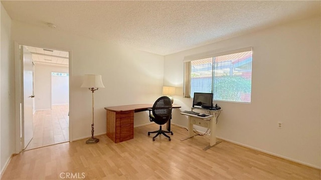 home office featuring a textured ceiling and light hardwood / wood-style floors