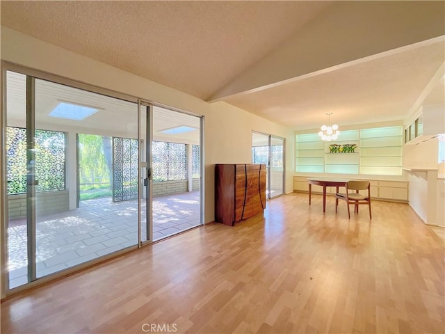 unfurnished dining area featuring built in shelves, light wood-type flooring, plenty of natural light, and an inviting chandelier