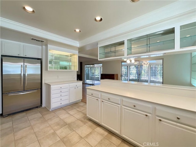 kitchen with light tile patterned floors, white cabinetry, ornamental molding, and stainless steel refrigerator