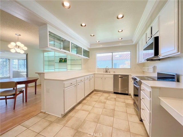 kitchen with a wealth of natural light, appliances with stainless steel finishes, decorative light fixtures, white cabinetry, and light tile patterned floors