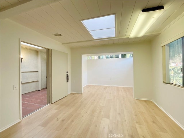 empty room featuring wood ceiling, a healthy amount of sunlight, and light hardwood / wood-style flooring