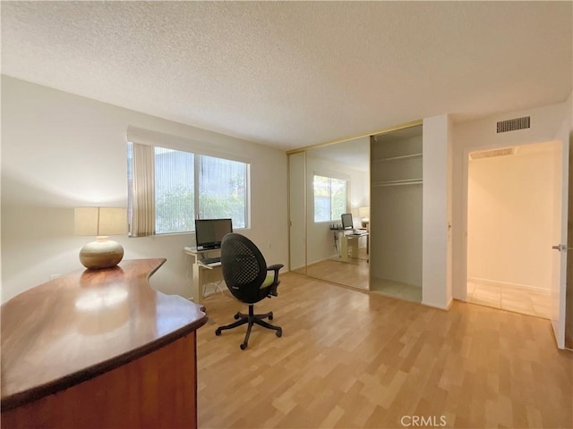 home office featuring a textured ceiling and light hardwood / wood-style floors