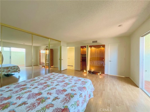 bedroom featuring hardwood / wood-style flooring, a textured ceiling, and a closet