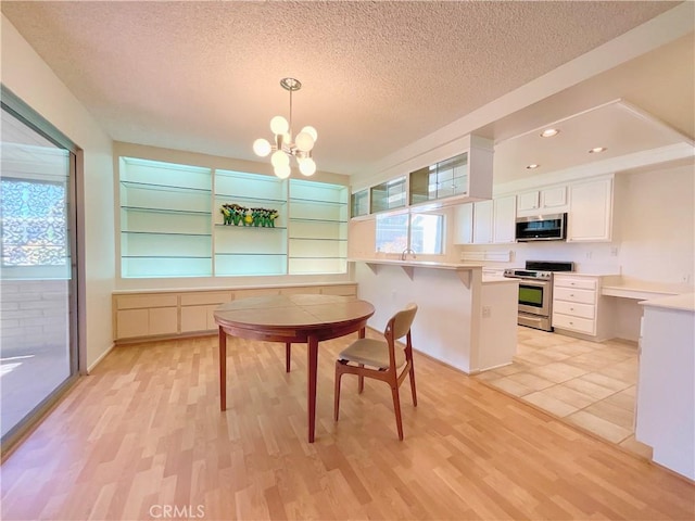 kitchen with decorative light fixtures, kitchen peninsula, a breakfast bar area, stainless steel appliances, and white cabinets