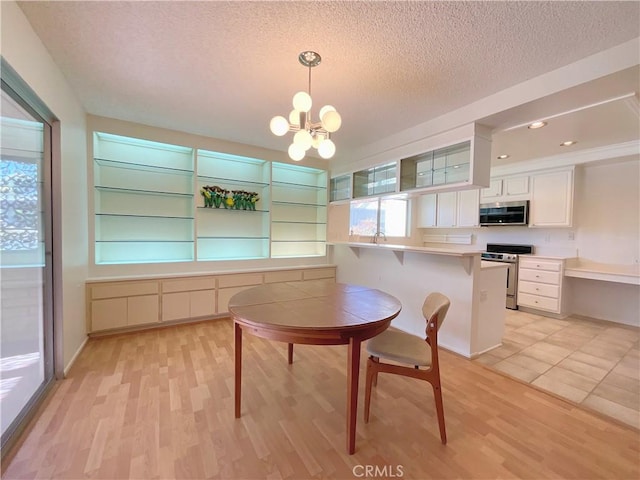 kitchen featuring kitchen peninsula, hanging light fixtures, a kitchen breakfast bar, stainless steel appliances, and white cabinets